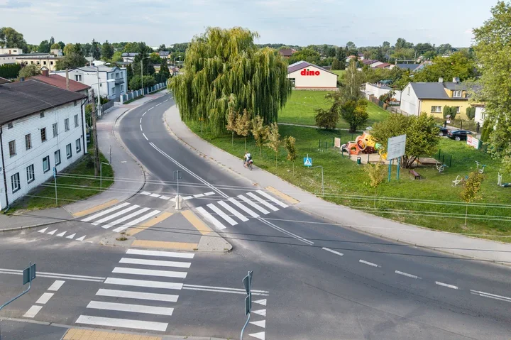 Widok z góry na skrzyżowanie z przejściami dla pieszych, plac zabaw i sklep Dino w małym mieście.